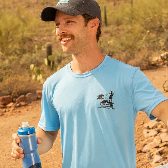 Front view of nan in performance T-shirt holding water bottle on a desert trail