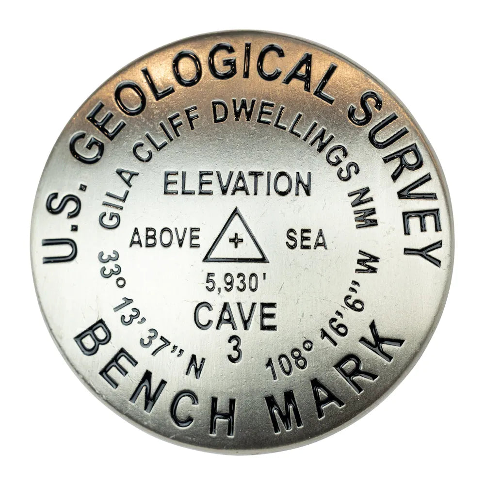 U.S. Geological Survey benchmark marker with elevation details for Gila Cliff Dwellings National Monument on a white background