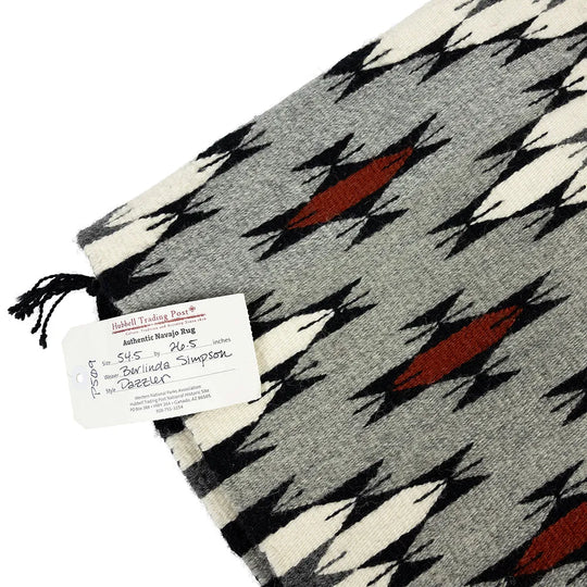 Navajo textile with geometric pattern and authenticity tag on a white background