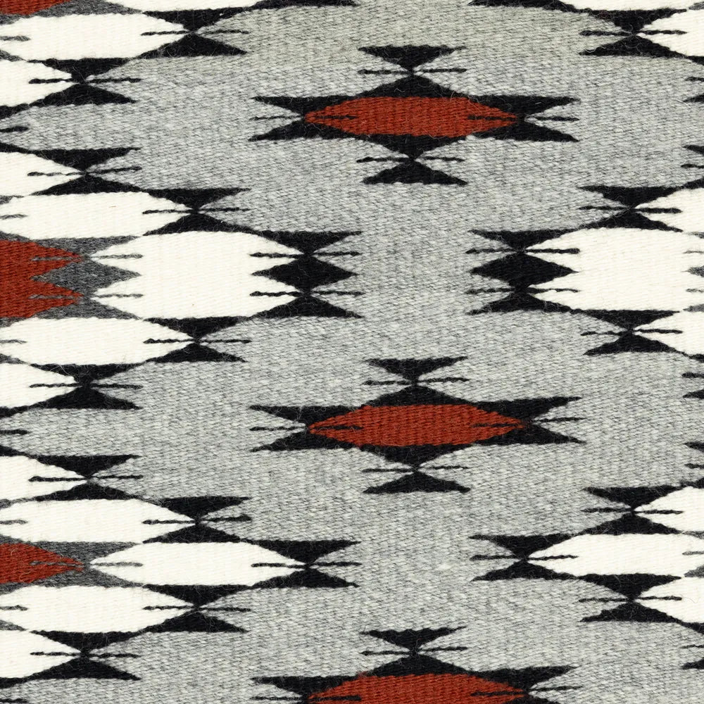 Close-up of a patterned fabric with geometric design in red, black, and white on gray background