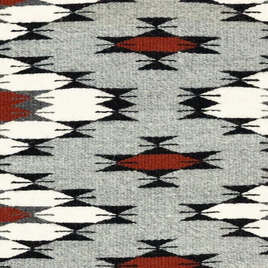 Close-up of a patterned fabric with geometric design in red, black, and white on gray background