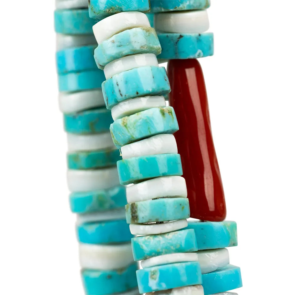 Navajo necklace closeup of turquoise and white cylindrical beads with a red cylindrical bead on a white background