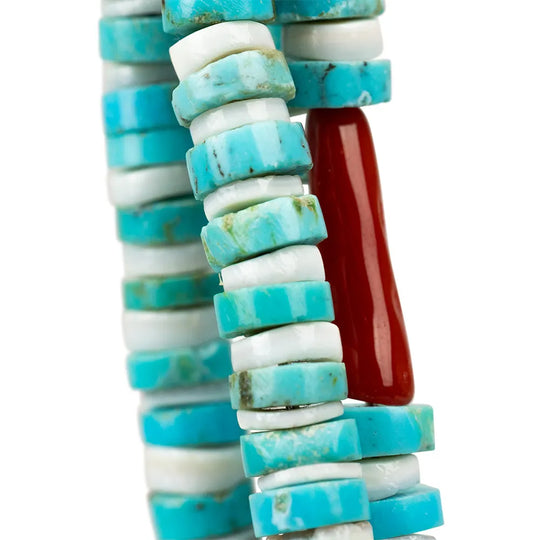 Navajo necklace closeup of turquoise and white cylindrical beads with a red cylindrical bead on a white background