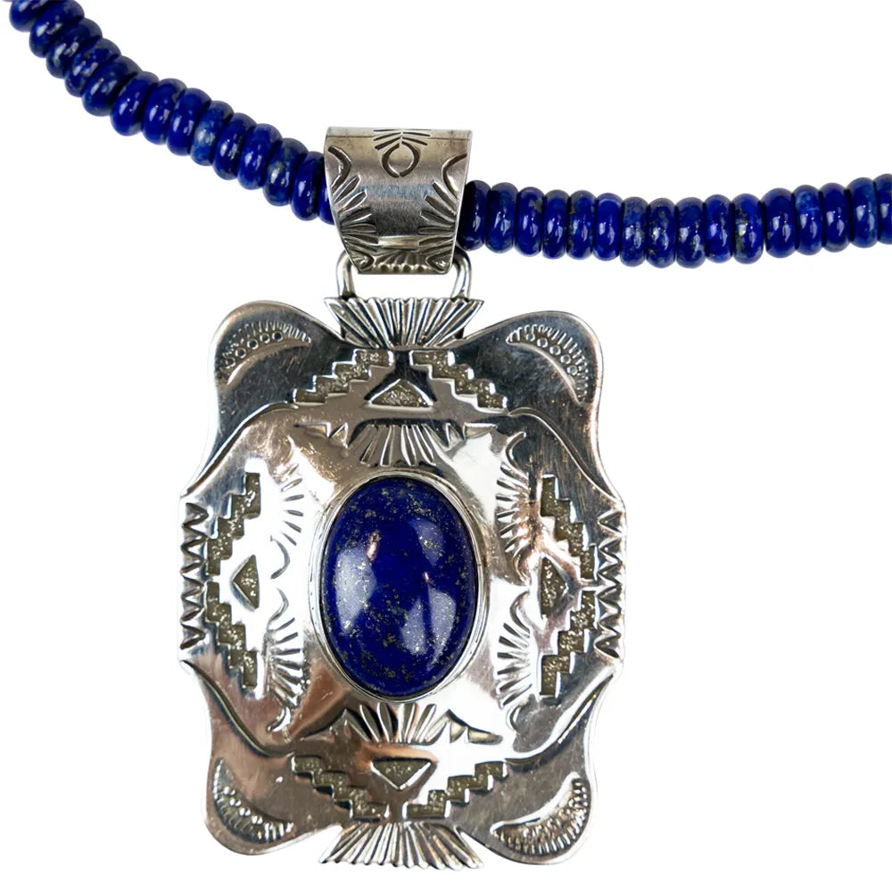 Silver pendant with blue stone on a blue beaded necklace against a white background