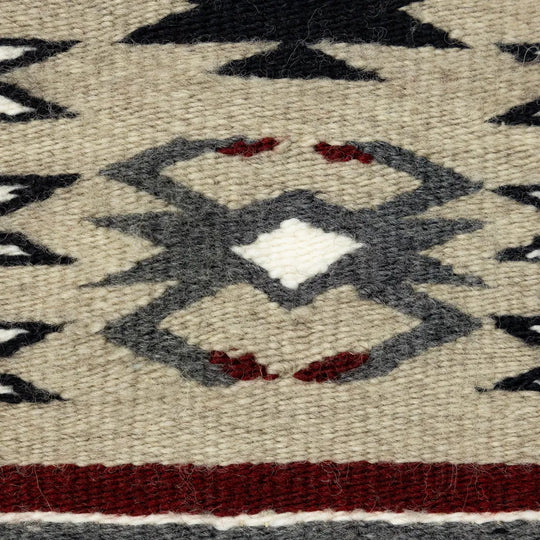 Detail of a woven textile with geometric pattern featuring black, gray, and red colors.