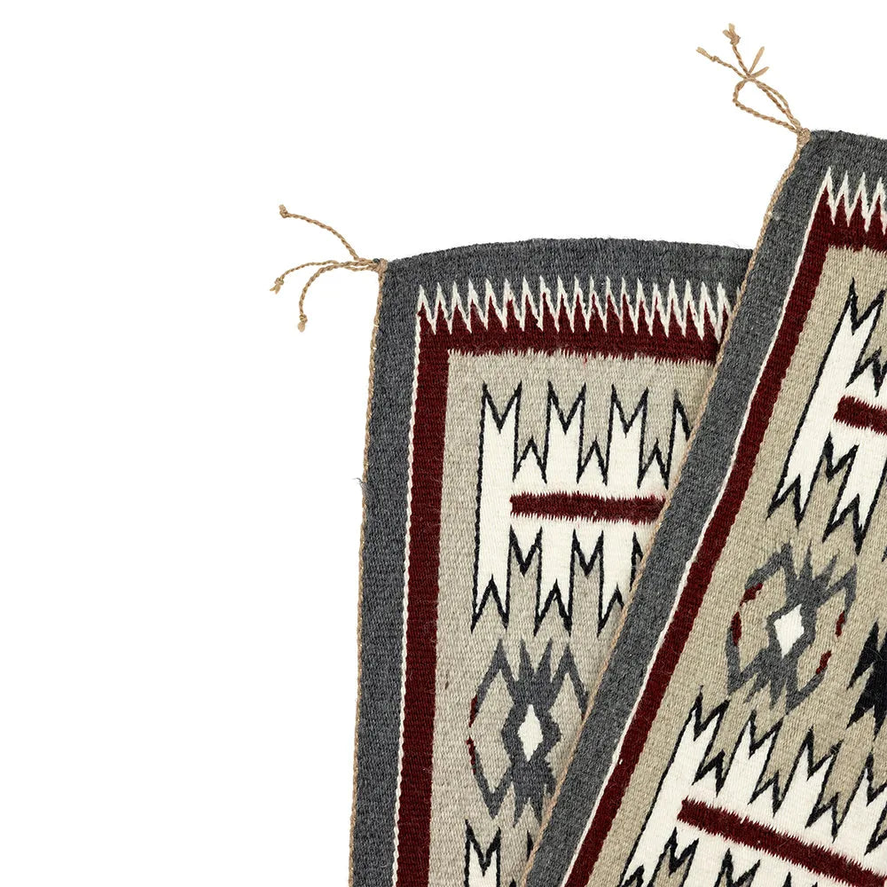 Close-up of the corners of a Navajo woven textile with geometric patterns on a white background