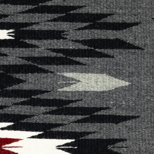 Close-up of a patterned fabric with black, white, and red colors on a dark background.