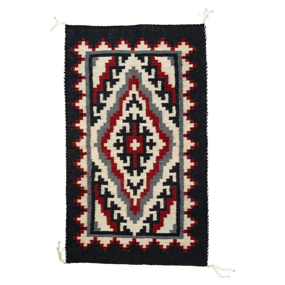Woven Navajo rug with geometric pattern on a white background