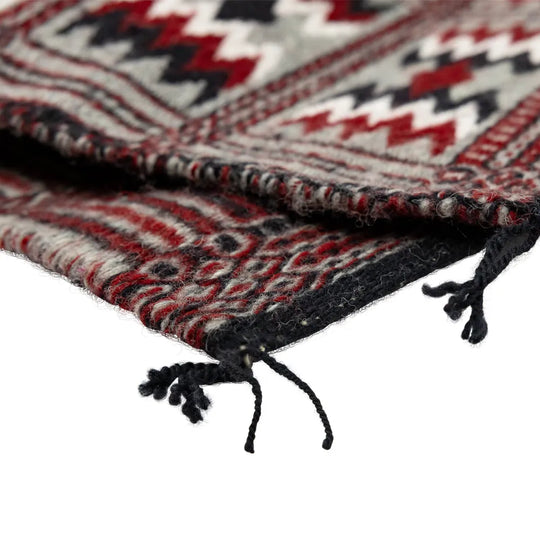 Extreme close-up of a patterned rug with red, black, and white colors on a white background.