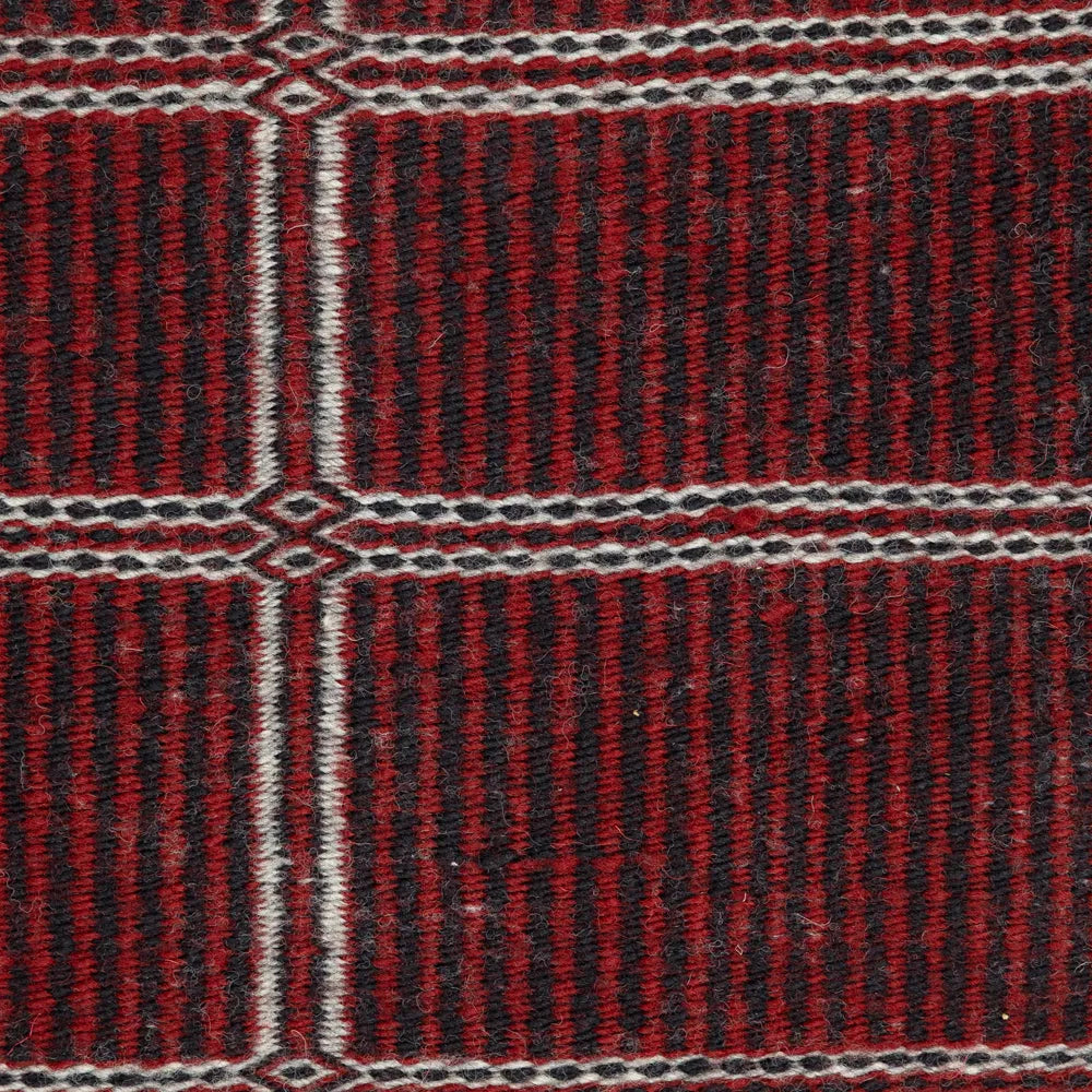 Close-up of side two of Navajo rug featuring a red and black woven pattern.