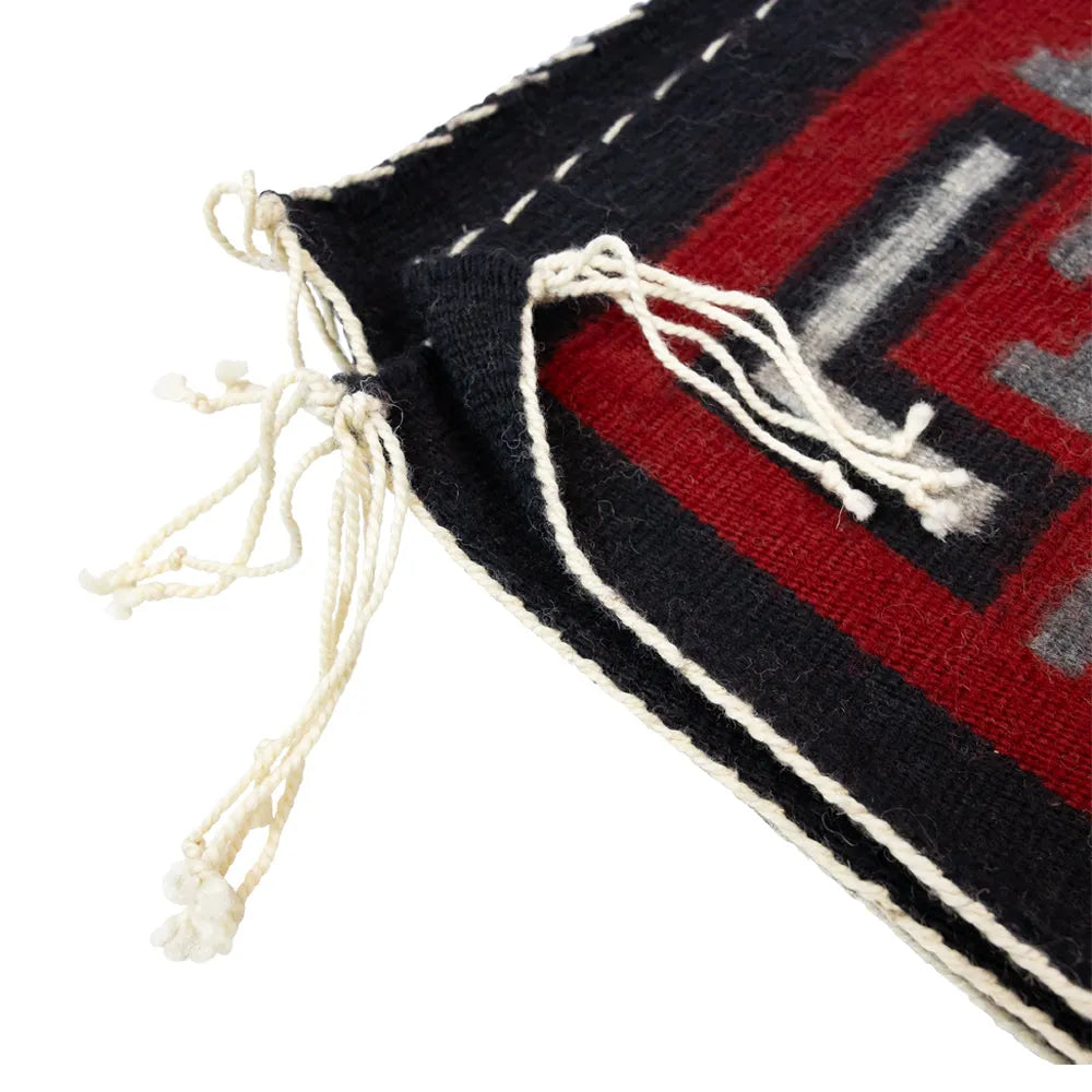 Close-up of a woven fabric with red, black, and white patterns on a white background