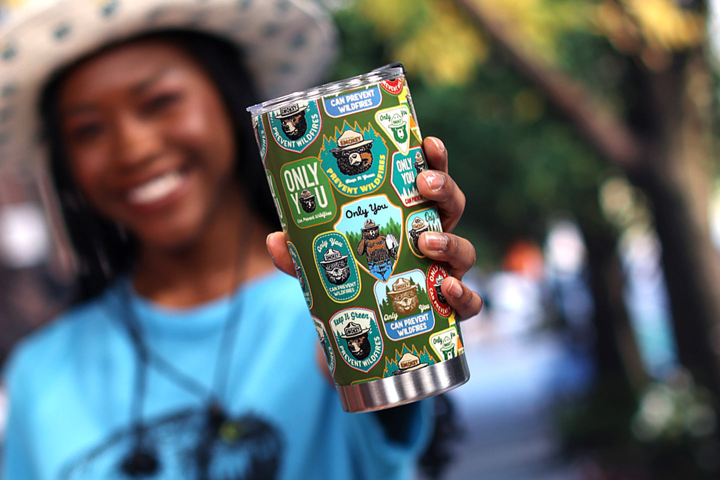 Woman holding out a Smokey Bear Insulated Tumbler