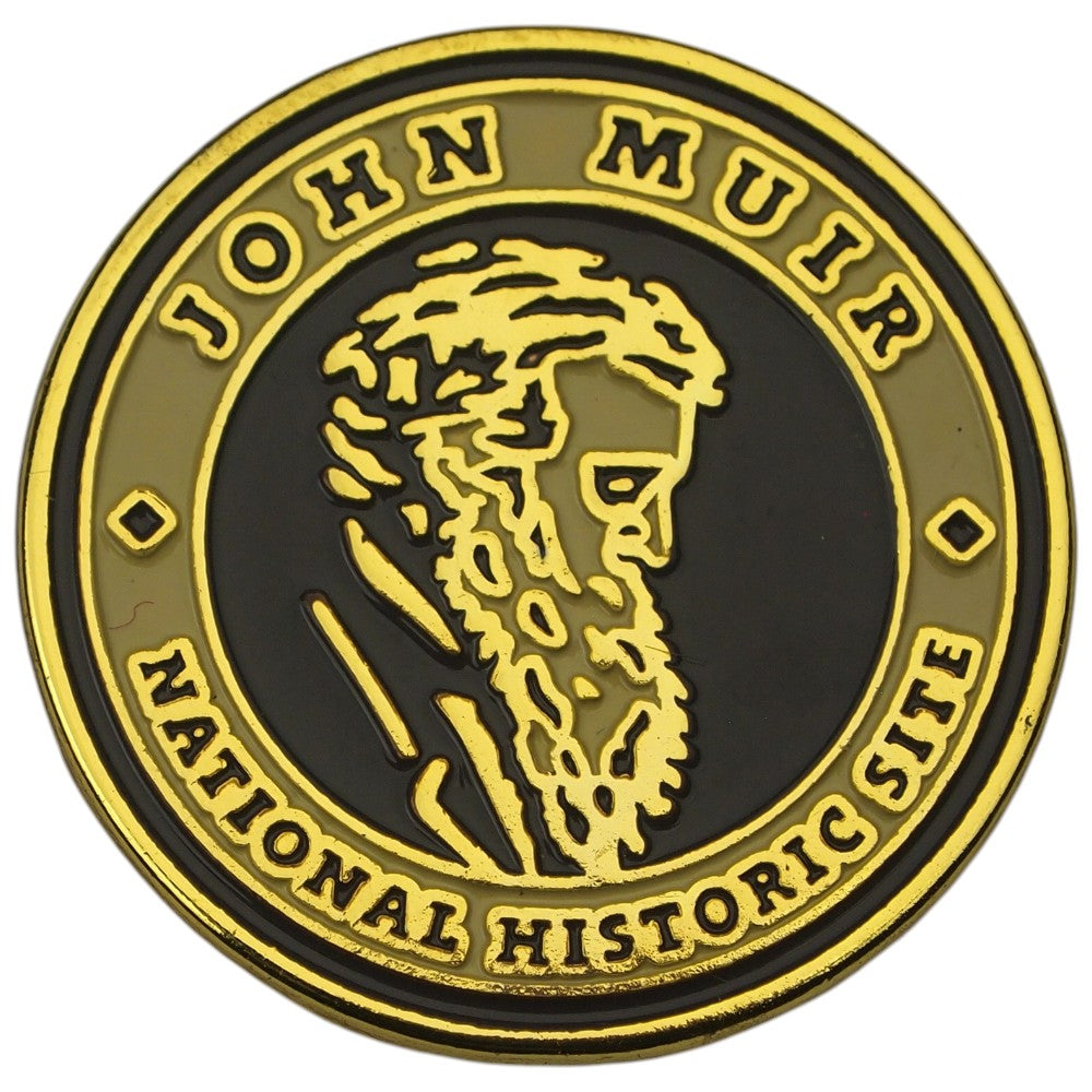 A circular commemorative pin with a black center, raised gold border, and gold lettering reading 'JOHN MUIR NATIONAL HISTORIC SITE,' plus a gold profile portrait in the middle, shown on a white background.
