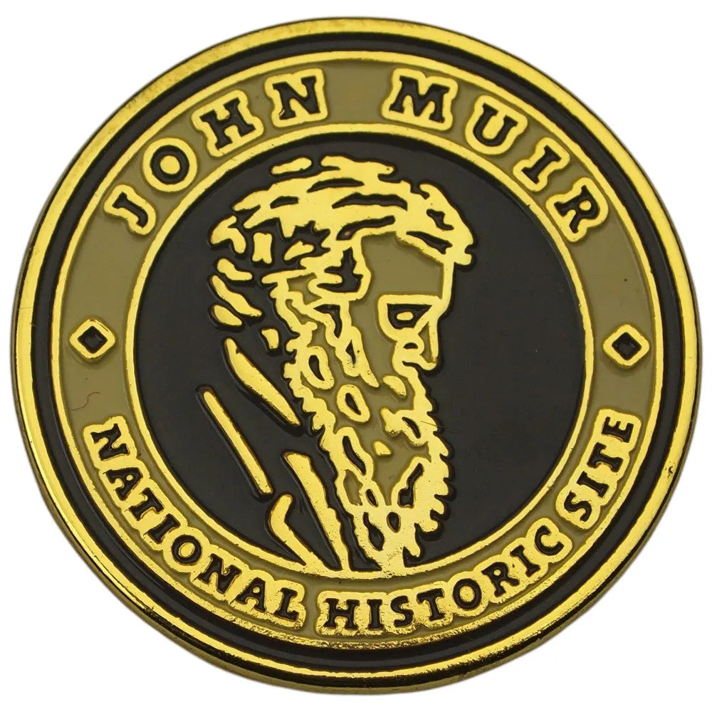 A circular commemorative pin with a black center, raised gold border, and gold lettering reading 'JOHN MUIR NATIONAL HISTORIC SITE,' plus a gold profile portrait in the middle, shown on a white background.