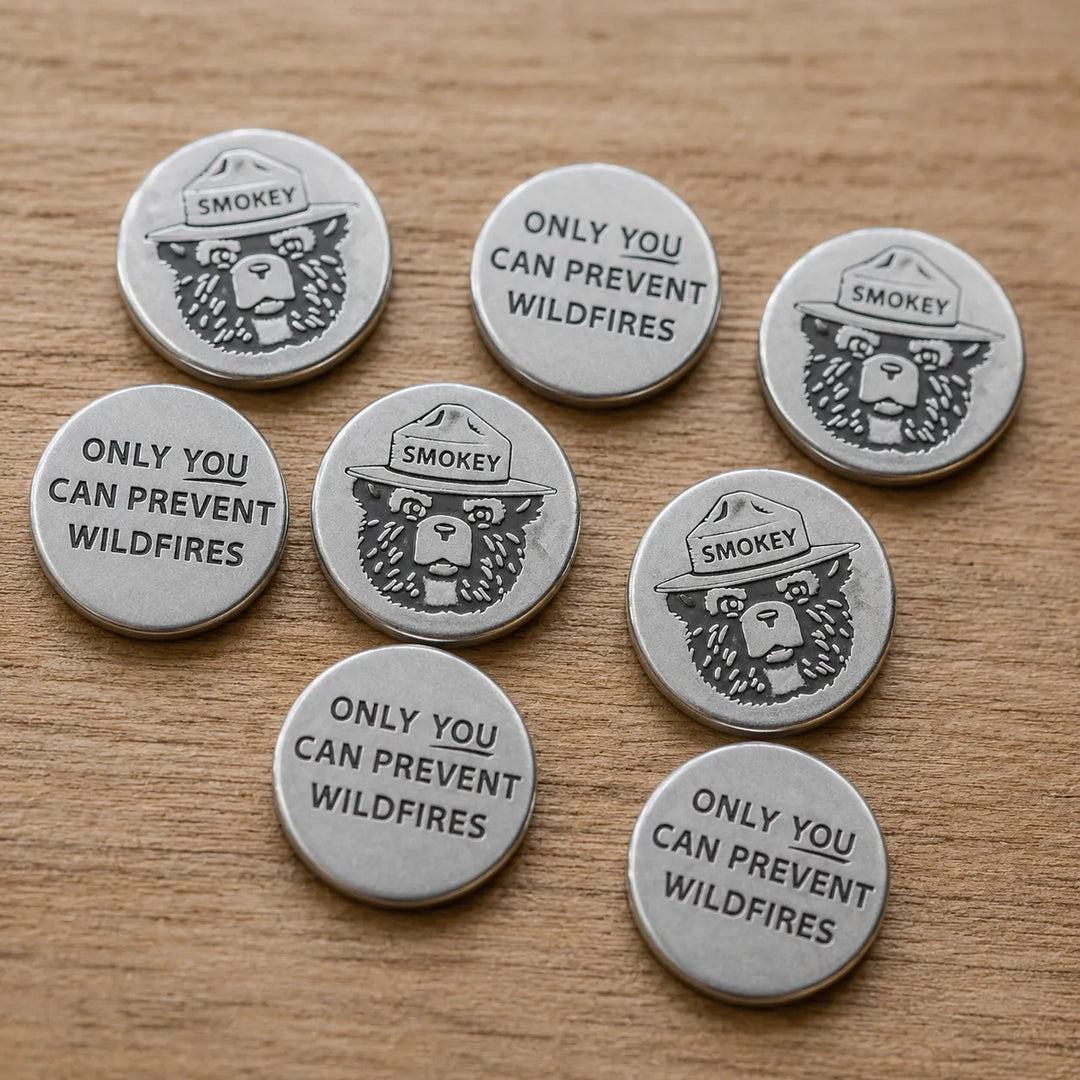 Seven round silver-toned metal fire starter tokens featuring the Smokey the Bear logo and the text &