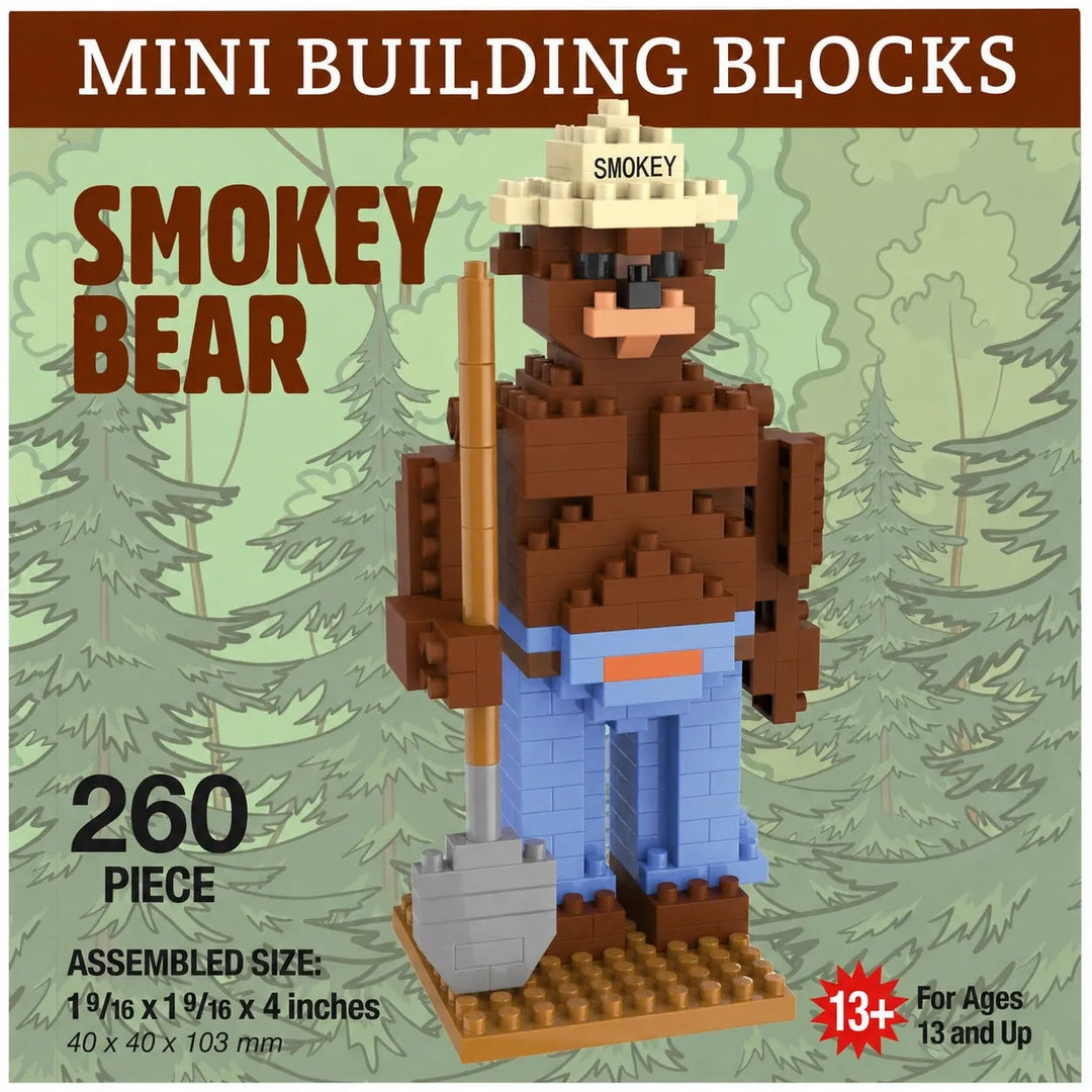 Mini building blocks set featuring a bear construction toy labeled 'SMOKEY BEAR,' assembled from 260 pieces. The bear wears a beige hat with 'SMOKEY' printed on it, dark brown fur, a tan shirt, blue pants, and holds a gray shovel.