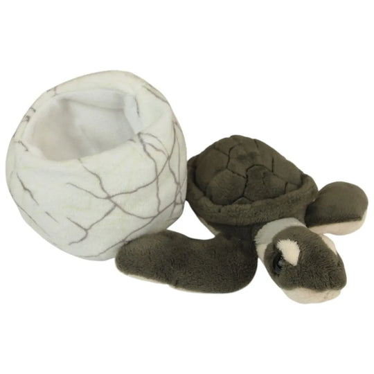 A plush turtle toy next to a matching cracked-egg-shaped nest on a plain white background.