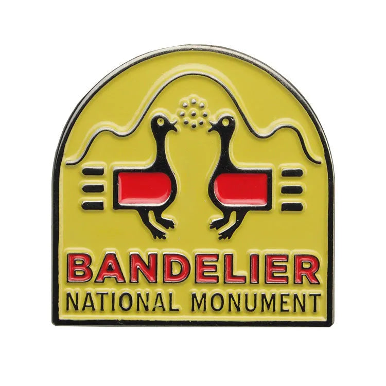Pin with Bandelier National Monument design featuring two birds and a yellow background