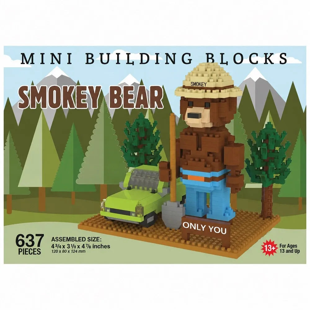 Box art for a mini building blocks set featuring a Smokey Bear character made from brown and tan blocks, wearing a straw hat and blue pants, standing beside a green car on a forest-themed illustrated background. Text includes 'MINI BUILDING BLOCKS', 'SMOKEY BEAR', '637 PIECES', and 'ASSEMBLED SIZE: 4 1/4 x 3 1/4 x 4 1/4 inches'.