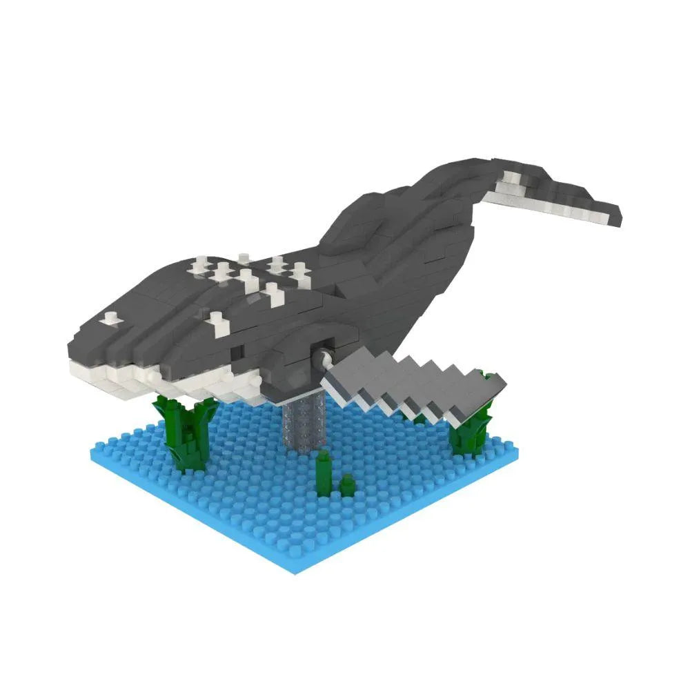Mini building blocks of a humpback whale with a blue baseplate and green blocks representing under water plants against a white background