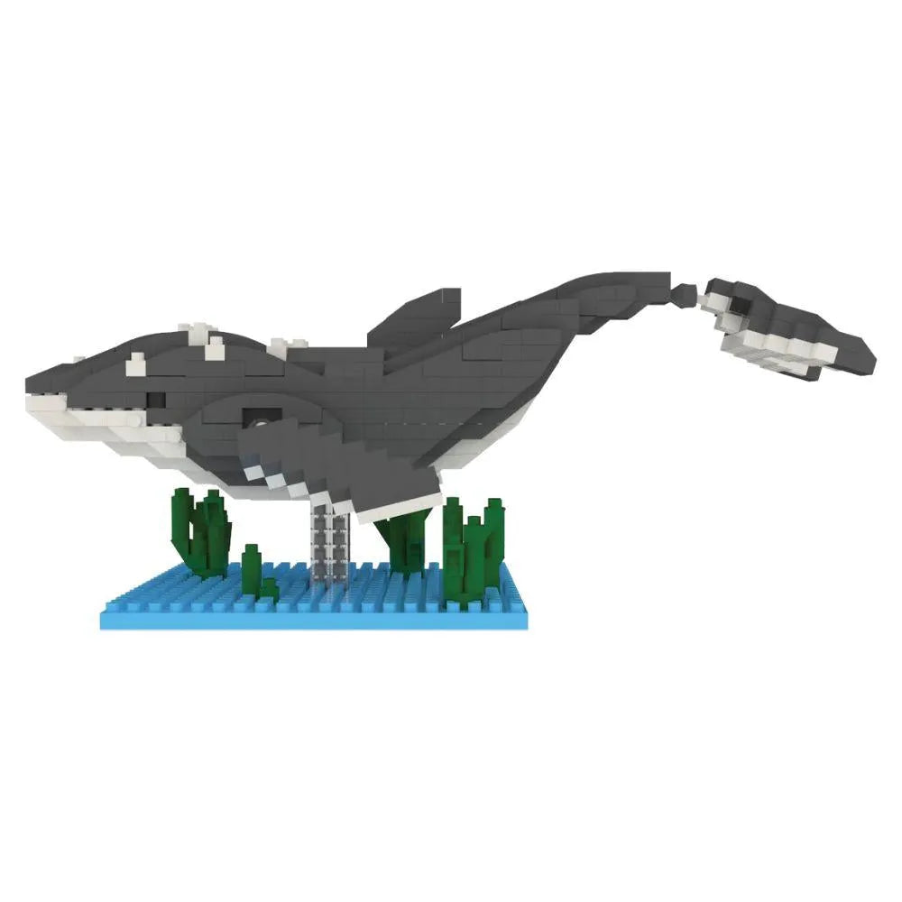 Mini building blocks of a humpback whale with a blue baseplate and green blocks representing under water plants against a white background