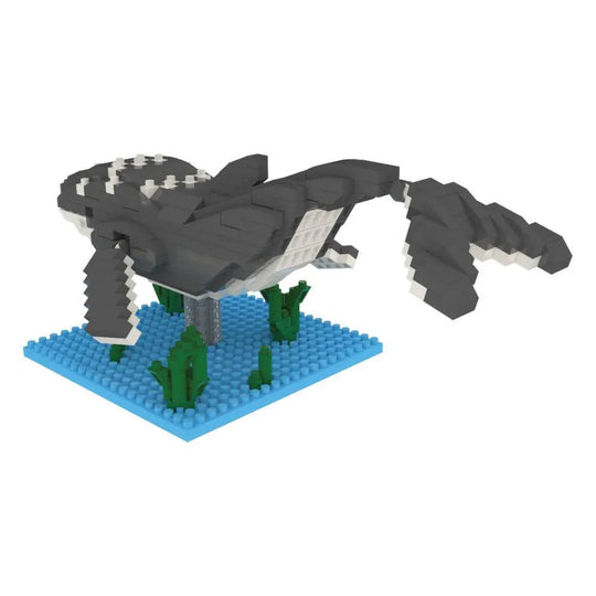 Mini building blocks of a humpback whale with a blue baseplate and green blocks representing under water plants against a white background