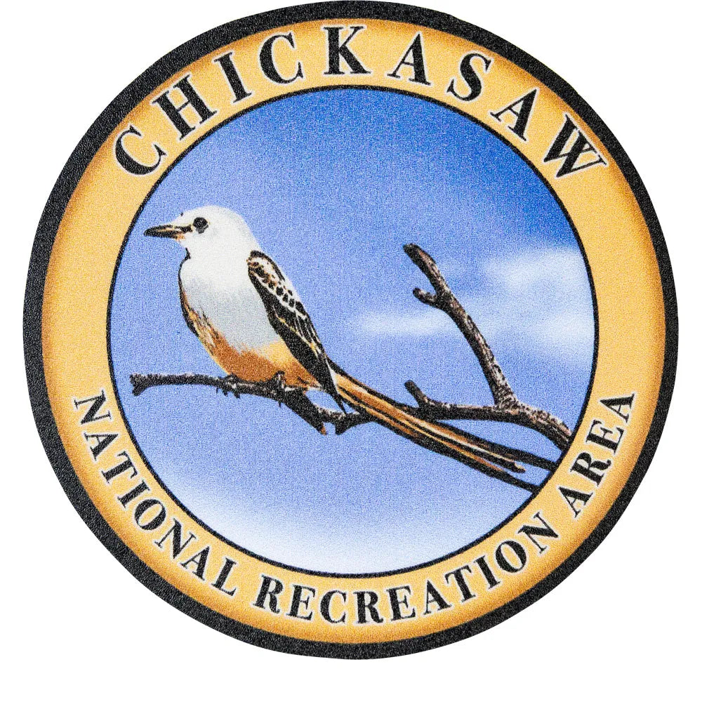 Logo of Chickasaw National Recreation Area with a bird on a branch against a blue sky.