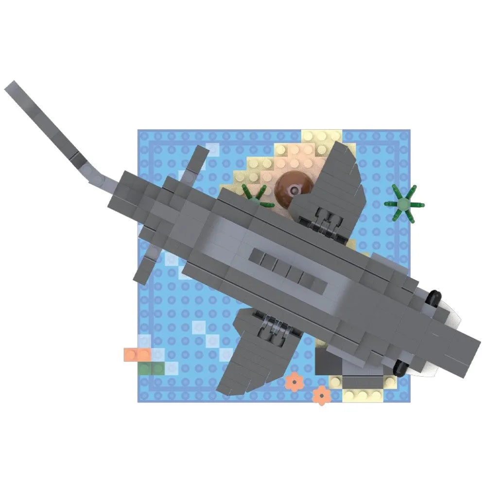 A gray brick-built shark toy shown from above on a blue patterned baseplate with small multicolored accessory pieces.