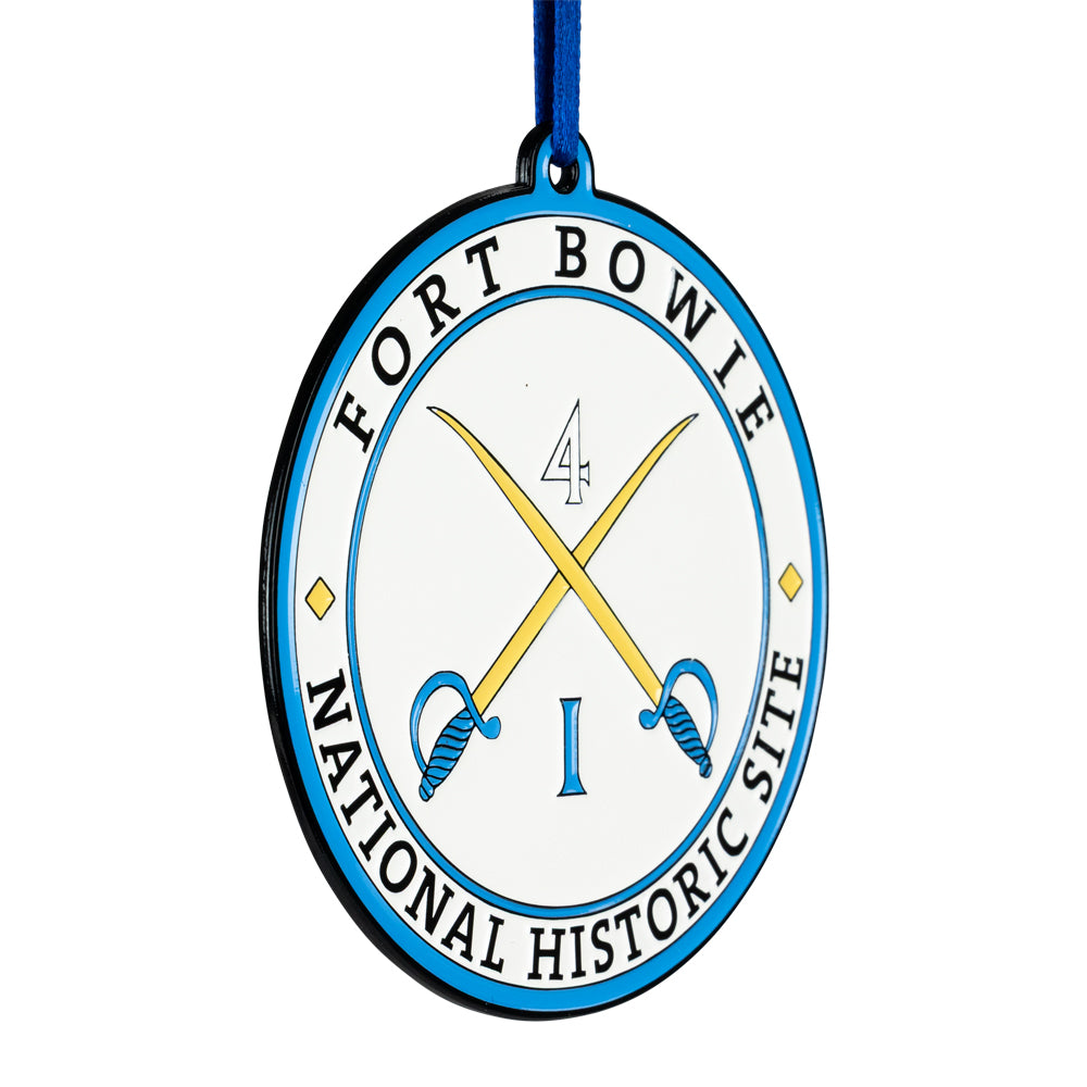 Circular metal ornament with 'Fort Bowle National Historic Site' text and crossed swords design on a white background.