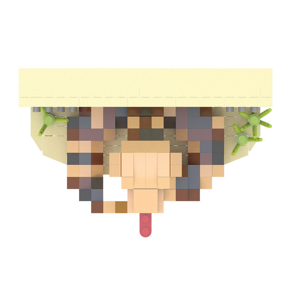 A pixelated, block-style toy figure or character model shown from above on a plain white background. The figure has a pale yellow top section, brown and beige pixelated body details, green side accents, and a small pink protruding element at the bottom.