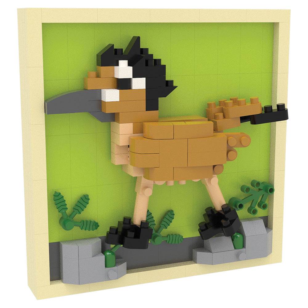 A small bird-shaped block-built display inside a square frame, featuring tan, black, gray, beige, and green toy bricks on a light gray background.