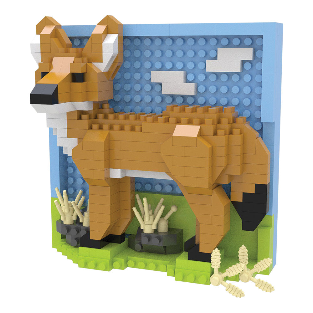 A block-built coyote sculpture made from interlocking toy bricks, standing on a green base with small decorative plants and a blue sky backdrop with white clouds.