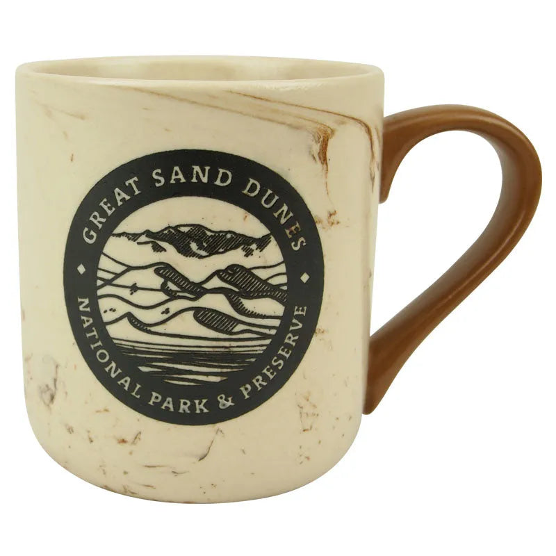 A beige marbled ceramic mug with a brown handle, featuring a round logo of Great Sand Dunes National Park and Preserve.