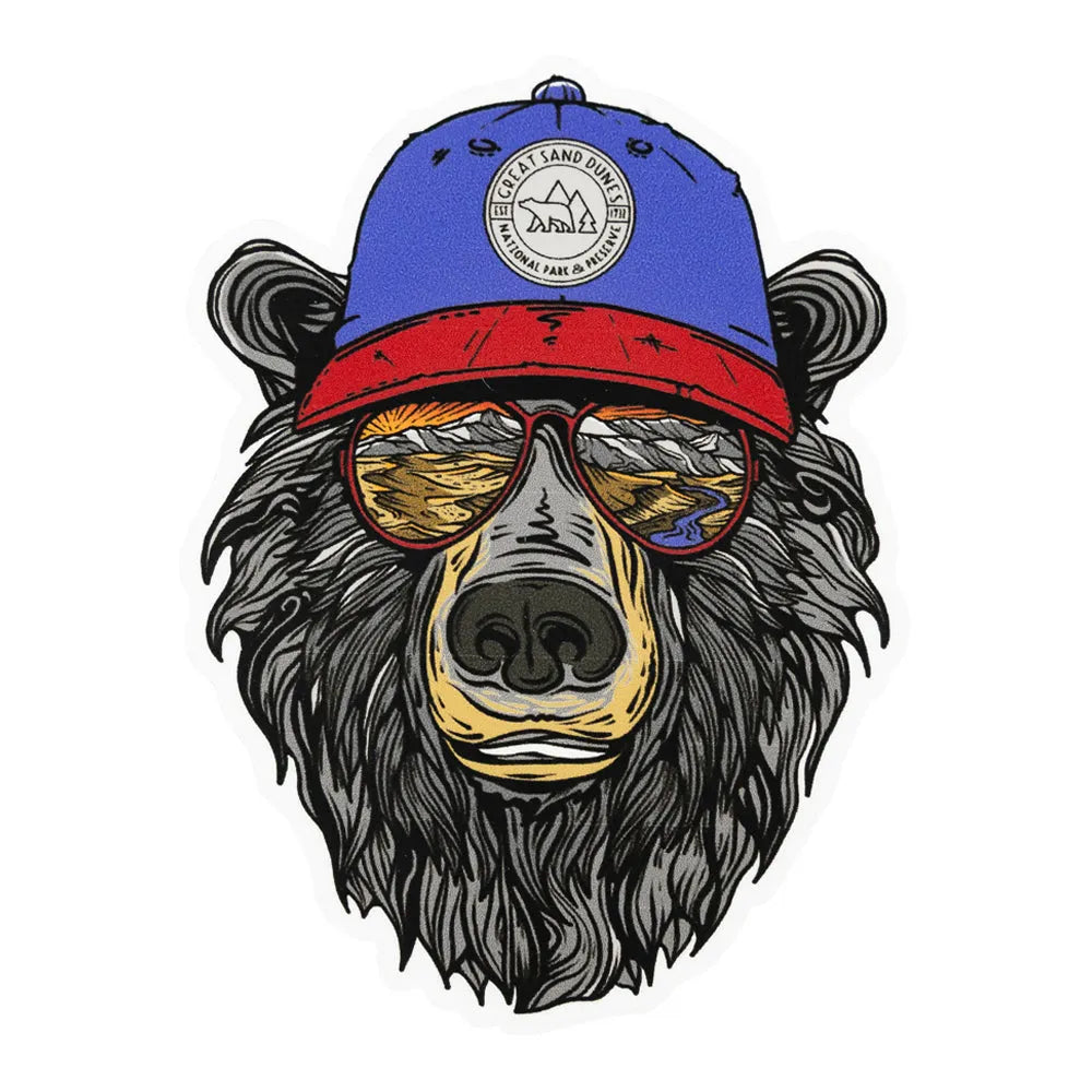 Illustration of a bear wearing a blue and red cap with a logo that reads "Great Sand Dunes National Park & Preserve" and sunglasses with a reflection of the park in them on a white background