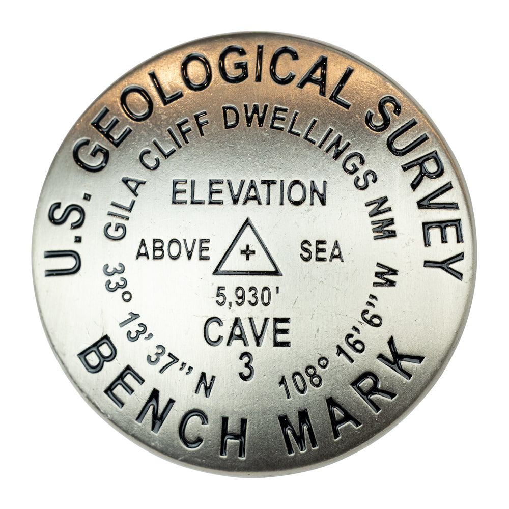 U.S. Geological Survey benchmark marker with elevation details for Gila Cliff Dwellings National Monument on a white background