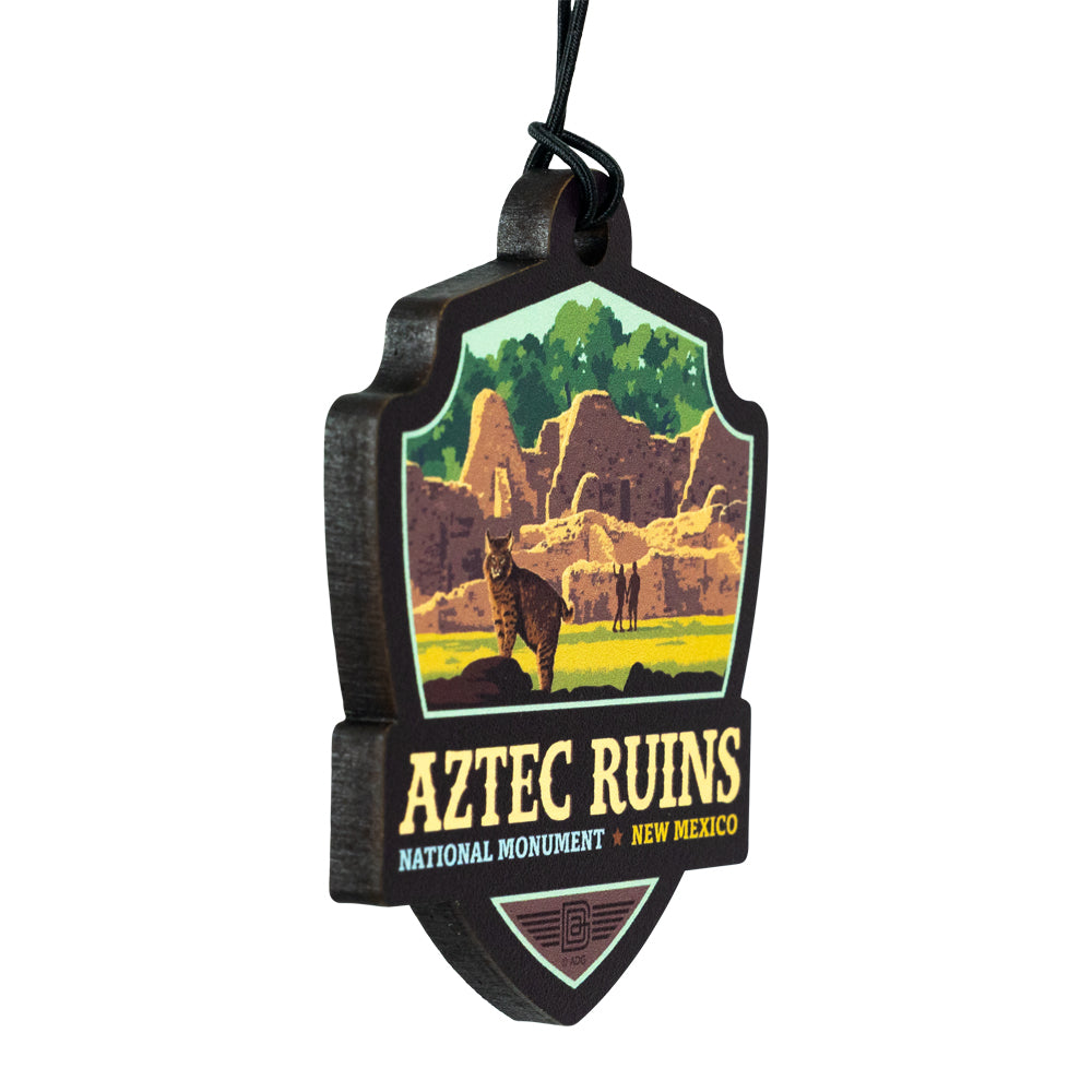 Decorative ornament of Aztec Ruins National Monument with scenic illustration and text.