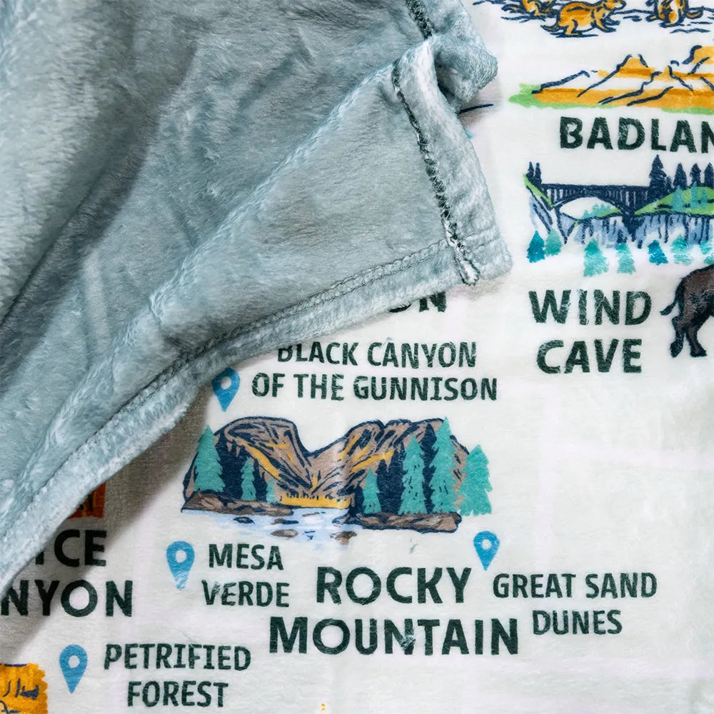Close-up of a fleece blanket with a map design featuring national parks on a white background.