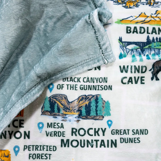 Close-up of a fleece blanket with a map design featuring national parks on a white background.