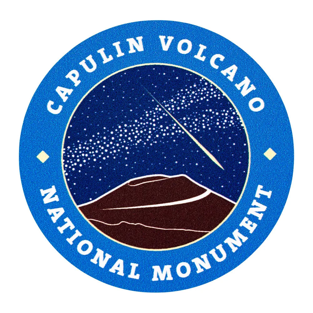 Round sticker of Capulin Volcano National Monument logo with mountain silhouette and starry night sky.