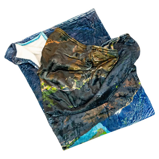 Folded fleece blanket with nature-themed pattern on a white background