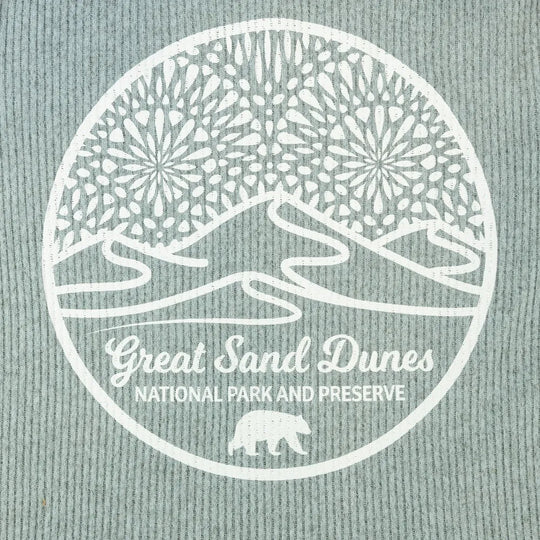 Logo closeup of Great Sand Dunes National Park and Preserve on a textured fabric background