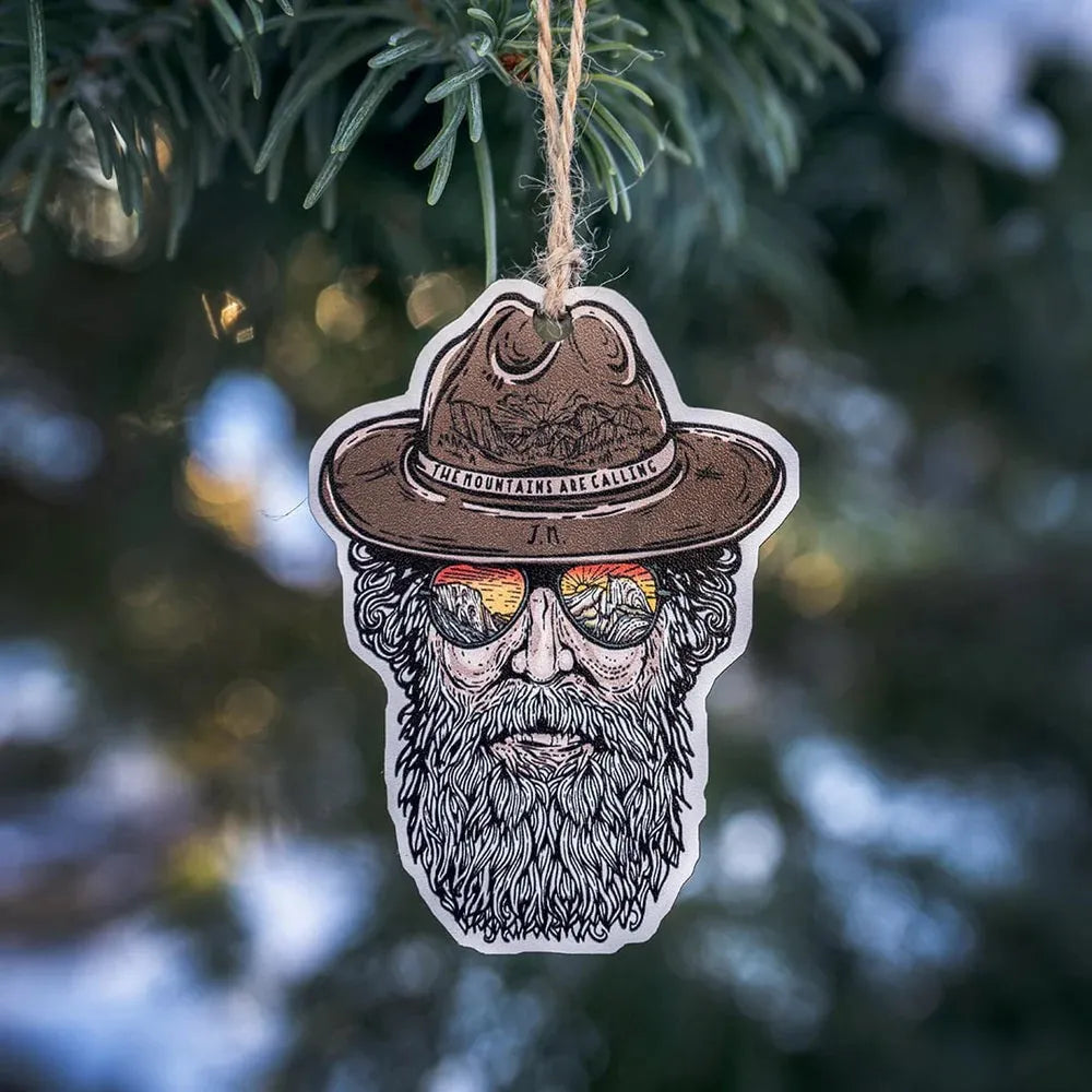 Decorative ornament with John Muir wearing a hat and sunglasses hanging on a tree.