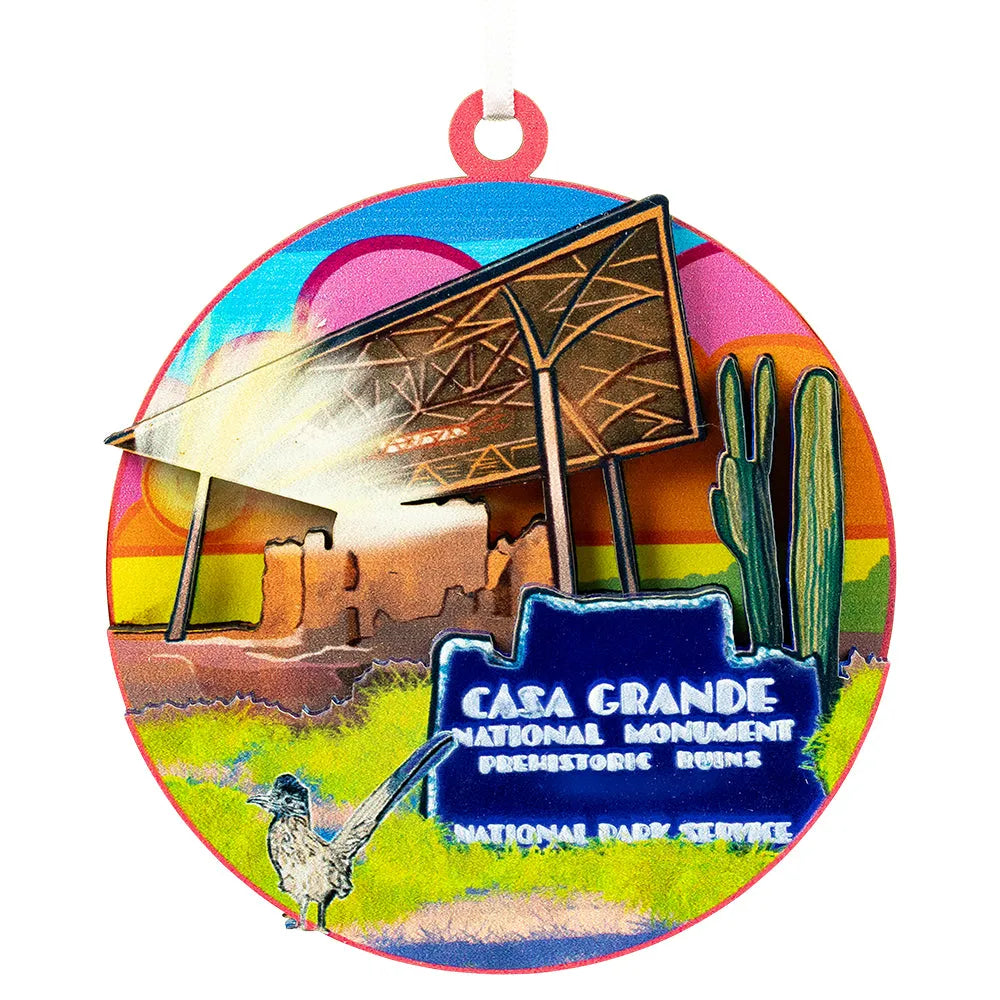Colorful round ornament with Casa Grande National Monument design featuring a prehistoric ruin, cactus, and desert landscape.
