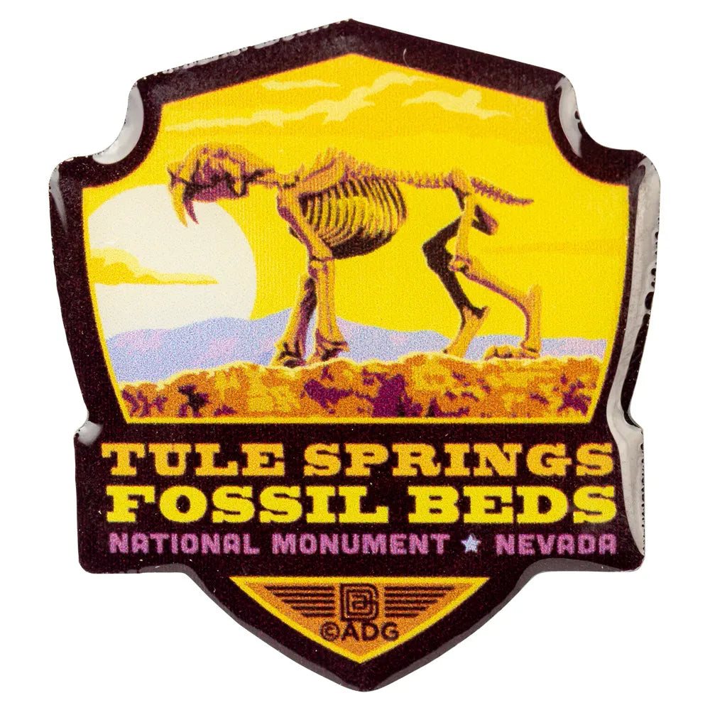 Pin with Tule Springs Fossil Beds National Monument logo featuring a saber-tooth tiger on a yellow background.