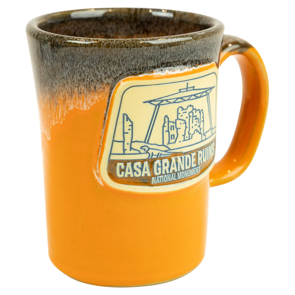 Orange mug with Casa Grande Ruins National Monument logo on a white background