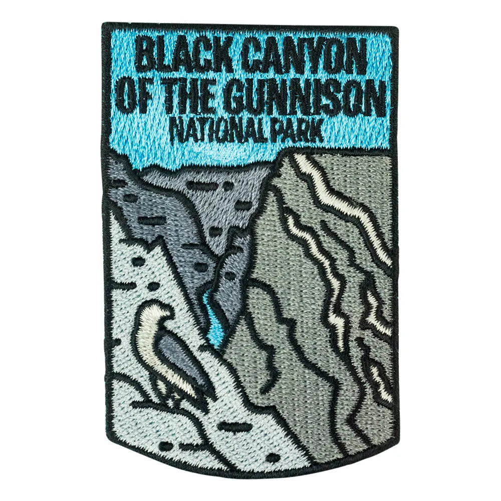 Embroidered patch featuring a landscape design of Black Canyon of the Gunnison National Park, with a light blue sky at the top and gray mountains, a river, and a bird below.