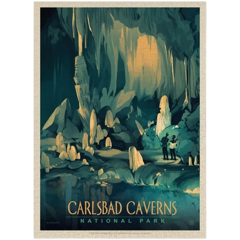 A completed vintage-style puzzle for Carlsbad Caverns National Park, showing an illustrated cave interior with stalactites and stalagmites in teal, dark blue, and warm beige tones. Two small figures stand near the cave entrance at the lower right.