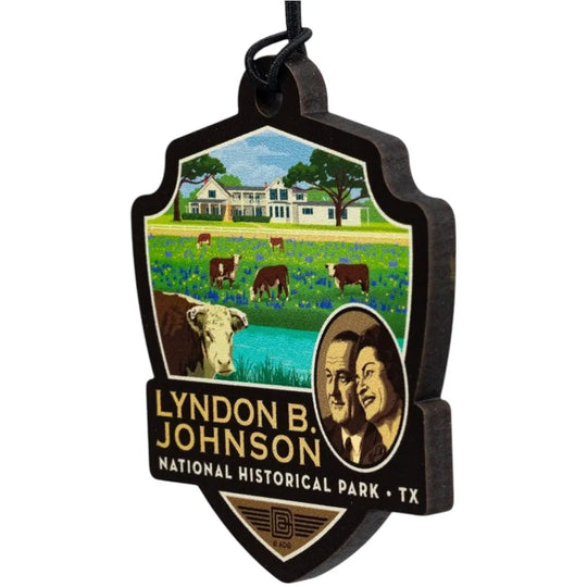 Badge-shaped ornament with Lyndon B. Johnson National Historical Park design featuring a farm scene and portraits.