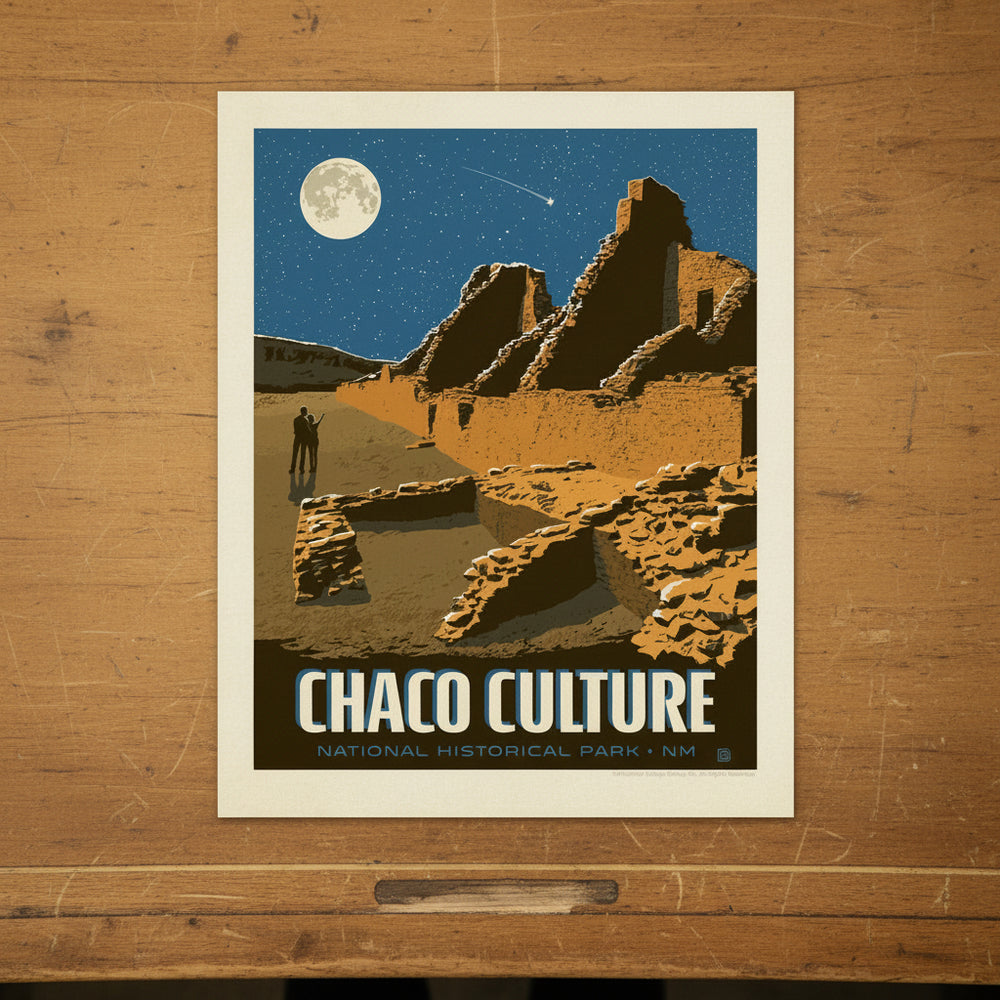 A vintage-style travel poster for Chaco Culture National Historical Park in New Mexico, featuring an illustration of ancient stone ruins under a dark blue night sky with a full moon and shooting star. It is lying on a drafting table.