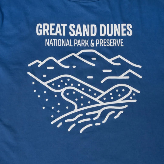 Blue t-shirt with white line art of sand dunes and text 'Great Sand Dunes National Park & Preserve' on a blue background.